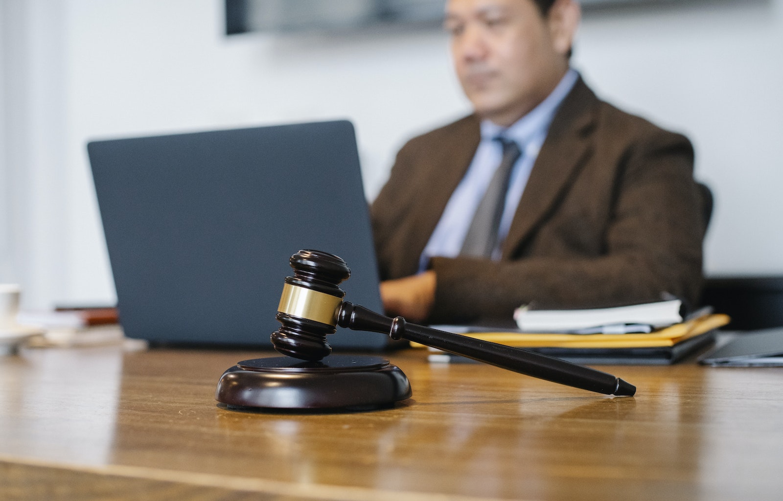 Photo by Sora Shimazaki Crop concentrated Asian male judge in formal clothes sitting using modern netbook while working in law office