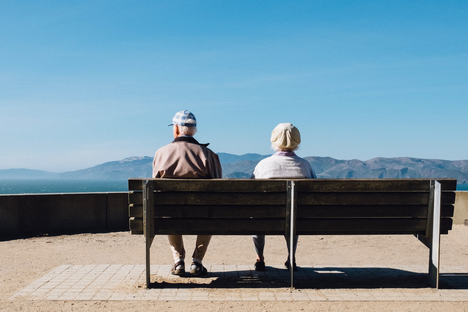 Photo by Matt Bennett man and woman sitting on bench facing sea